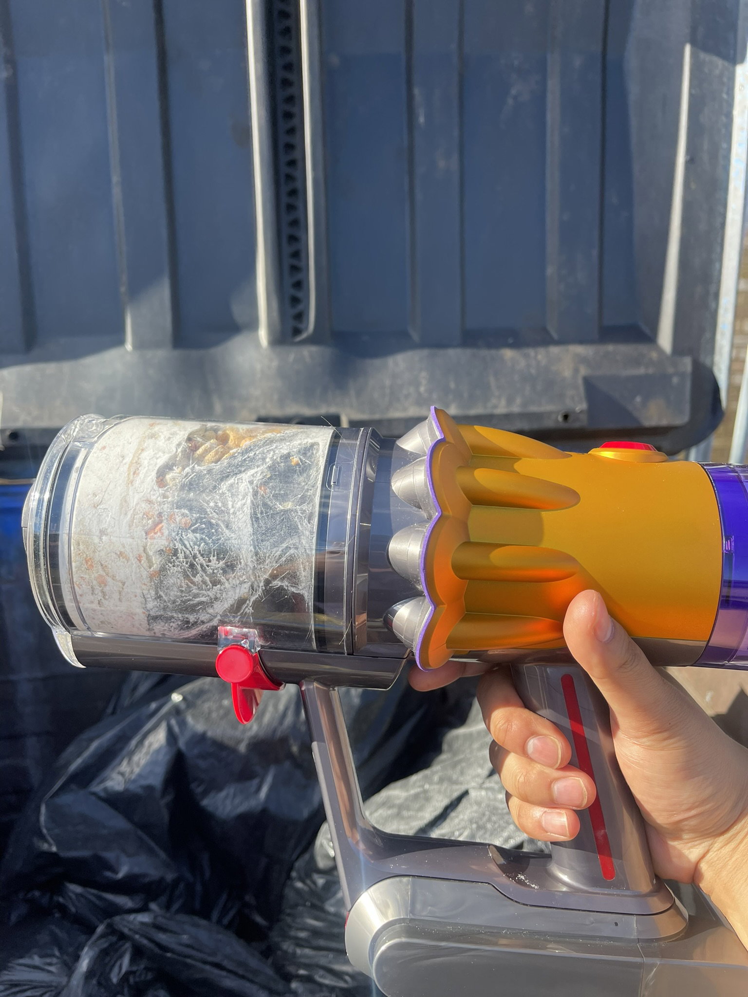 Dyson V12 Detect Slim's dustbin in front of a waste bin