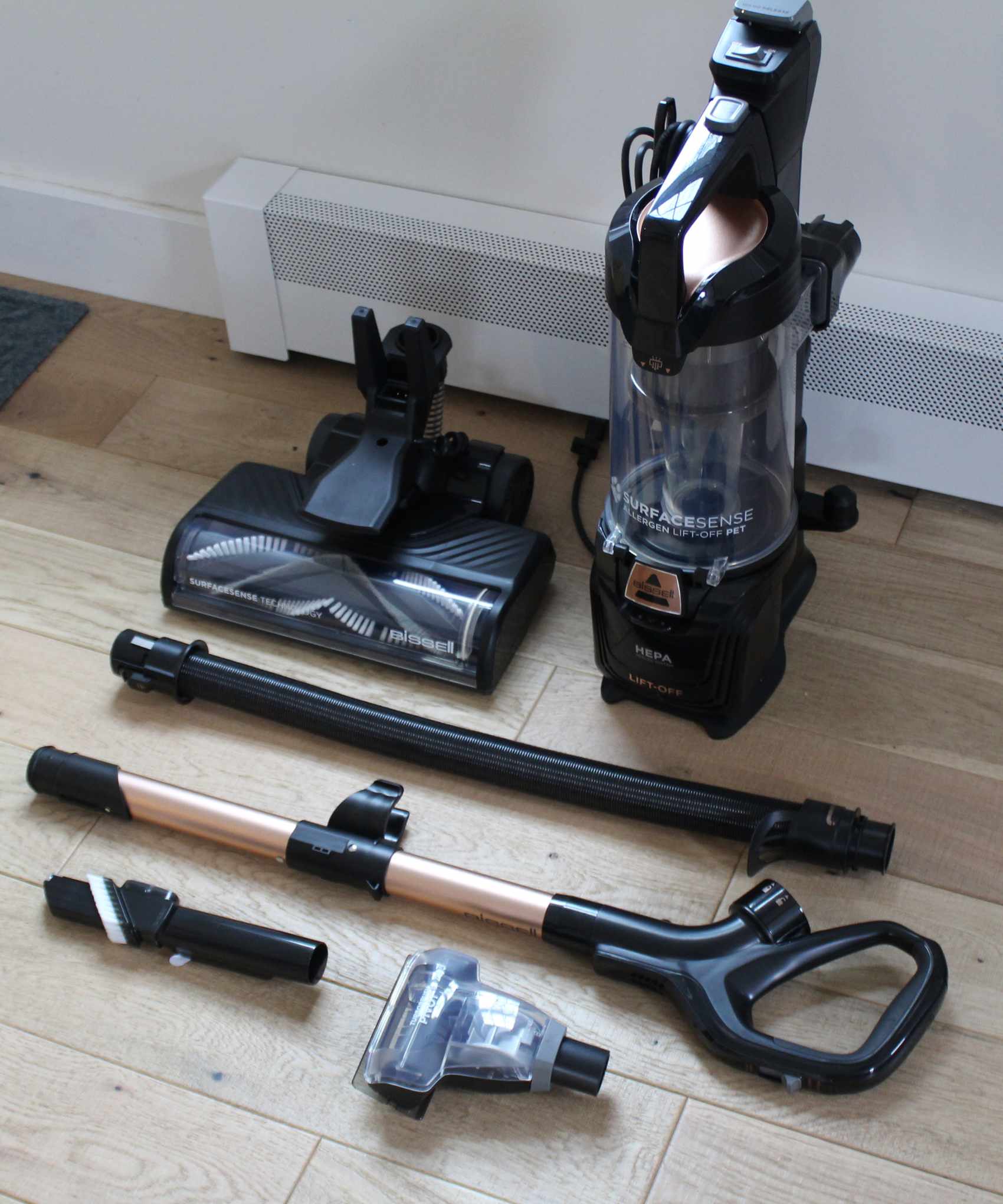 All unassembled parts of the Bissell SurfaceSense Allergen Pet Lift-Off Upright Vacuum on wooden floor in Camryn's home
