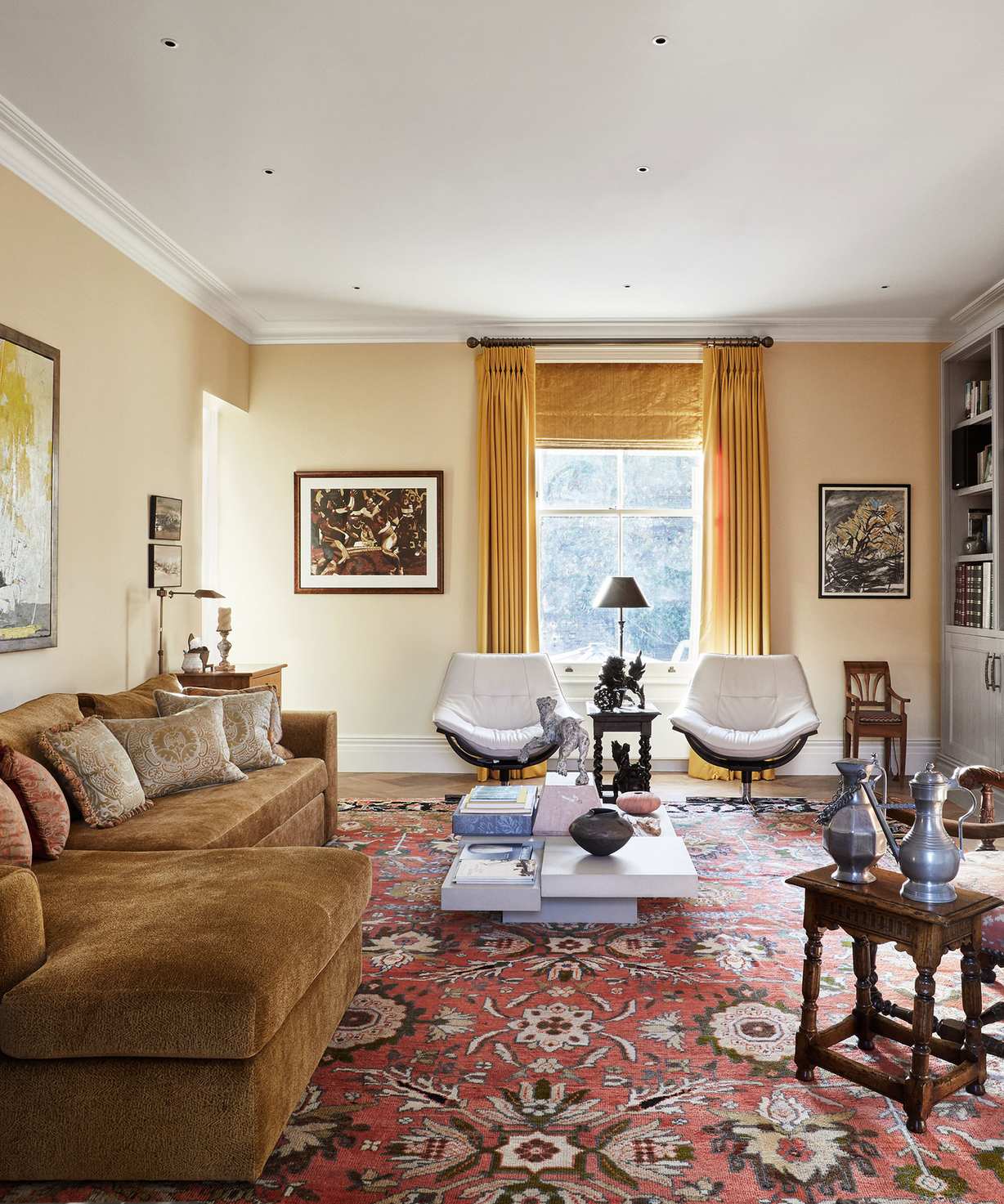 soft yellow living room with a velvet ochre couch, yellow window treatments, and a large patterned terracotta rug with two armchairs and a contemporary coffee table sat on top