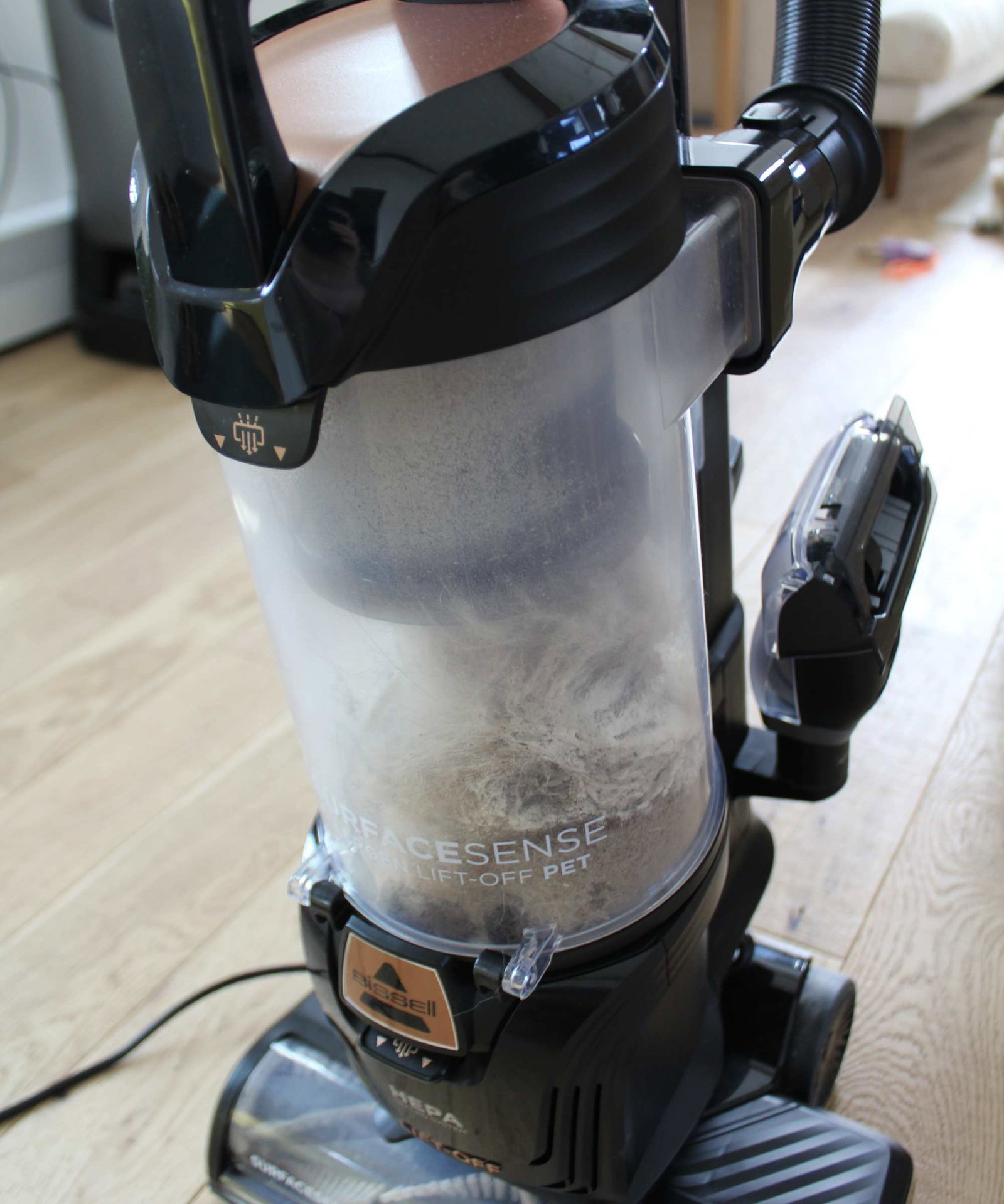 Closeup of the Bissell SurfaceSense Allergen Pet Lift-Off Upright Vacuum dustbin partially filled with dust and hair in Camryn Rabideau's home