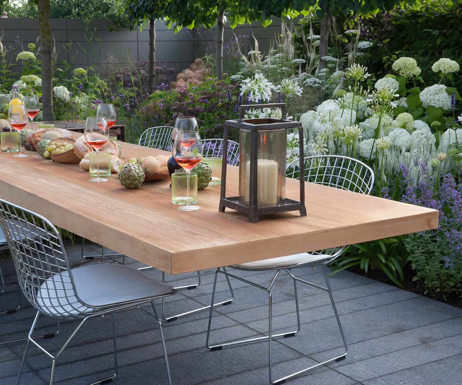 view of patio with outdoor dining furniture floating table and chairs outdoor living flower borders with hydrangeas