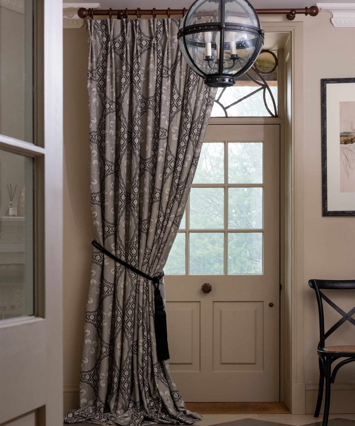 Hallway with front door covered with door curtain, metal and glass rounded pendant light, black &amp;amp; white checkered flooring
