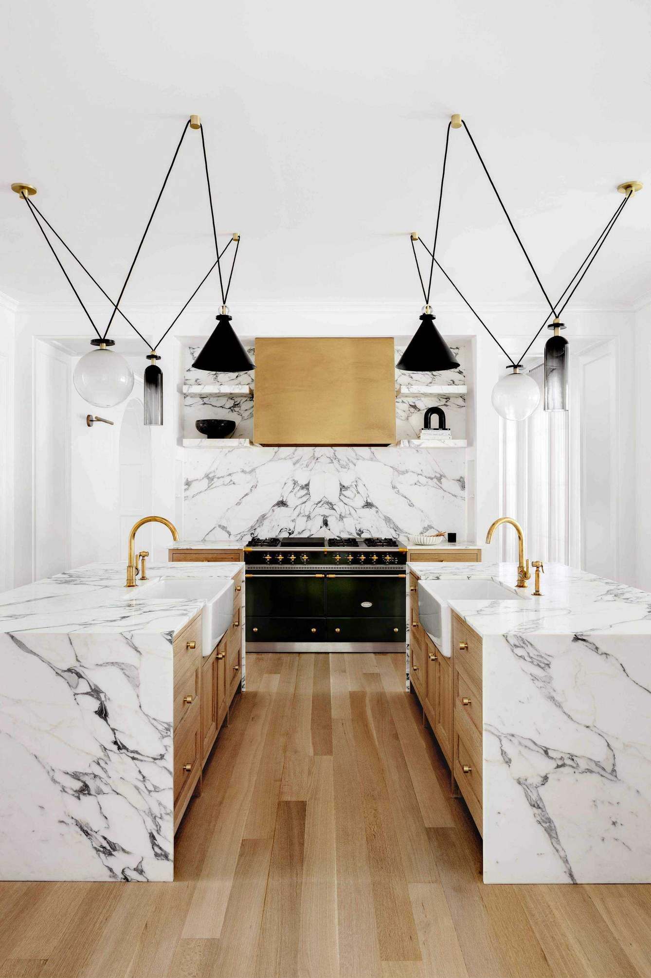 kitchen with marble surfaces and double islands with matching Belfast sinks with contemporary pendant lighting above and range cooker
