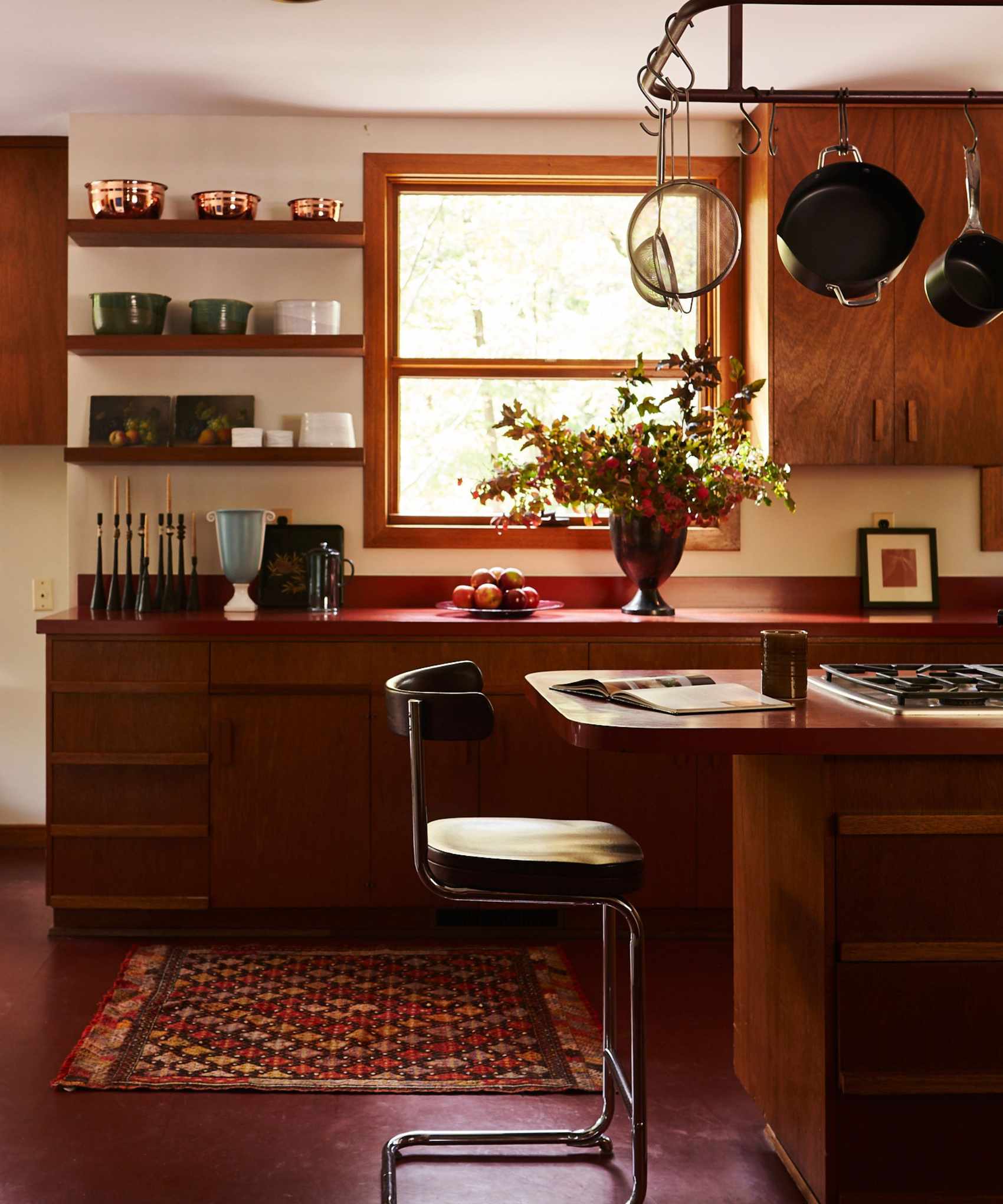 Midcentury kitchen with wood cabinets and wood island, midcentury stools and china and pottery on sehlves