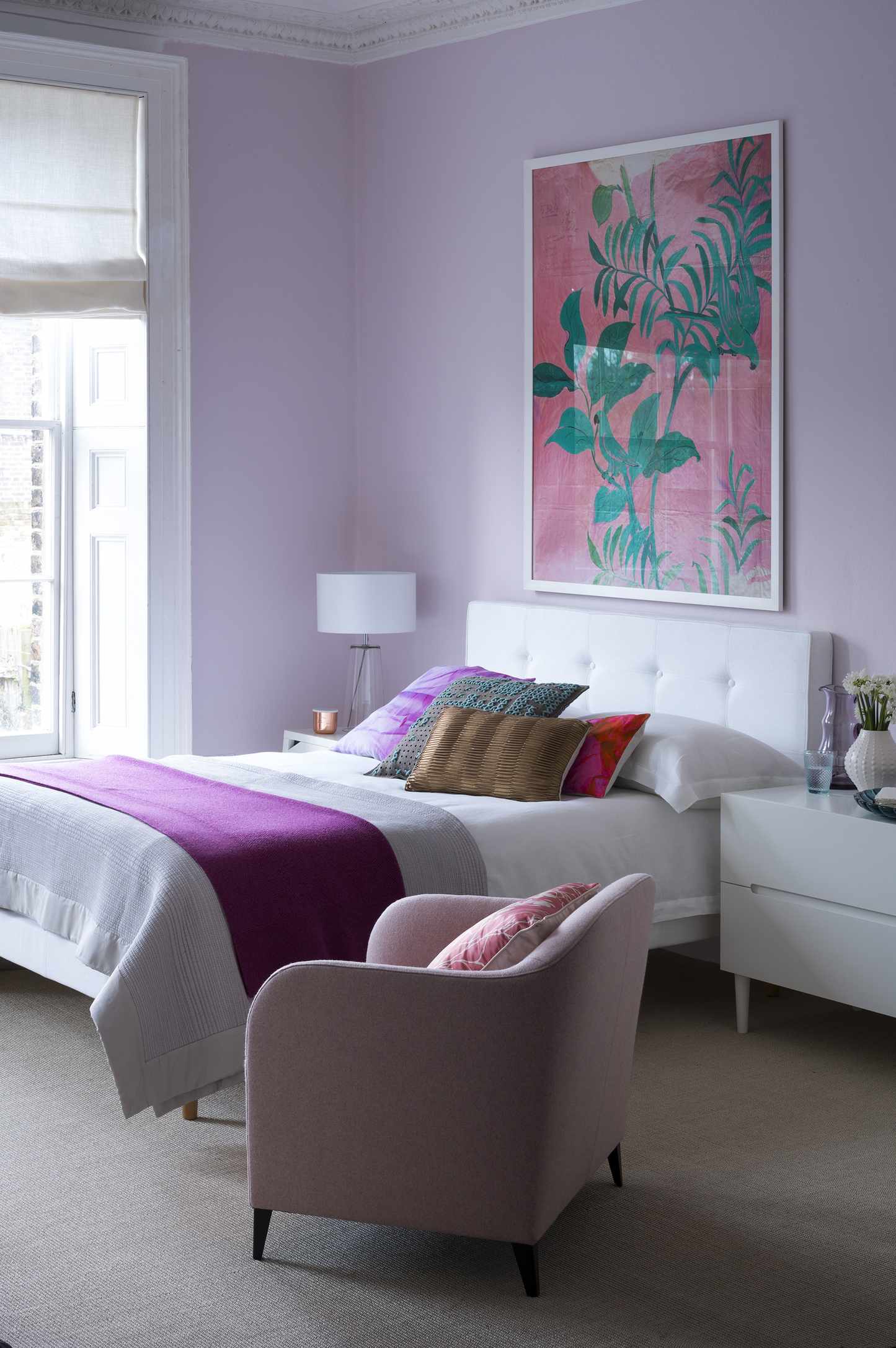 Lilac bedroom with artwork, white bed linen and colorful cushions