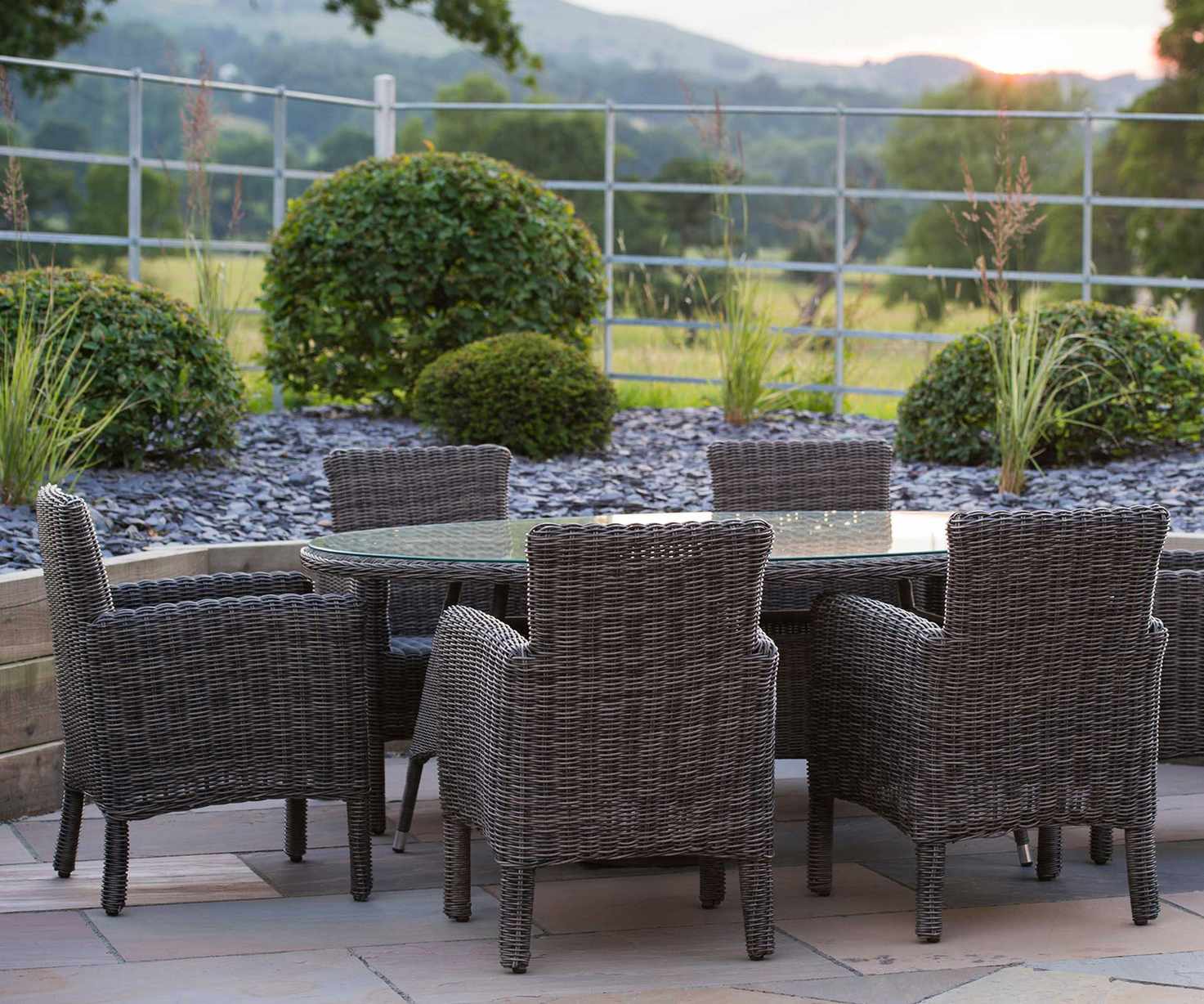 topiary evergreens around modern seating space with a view over fields