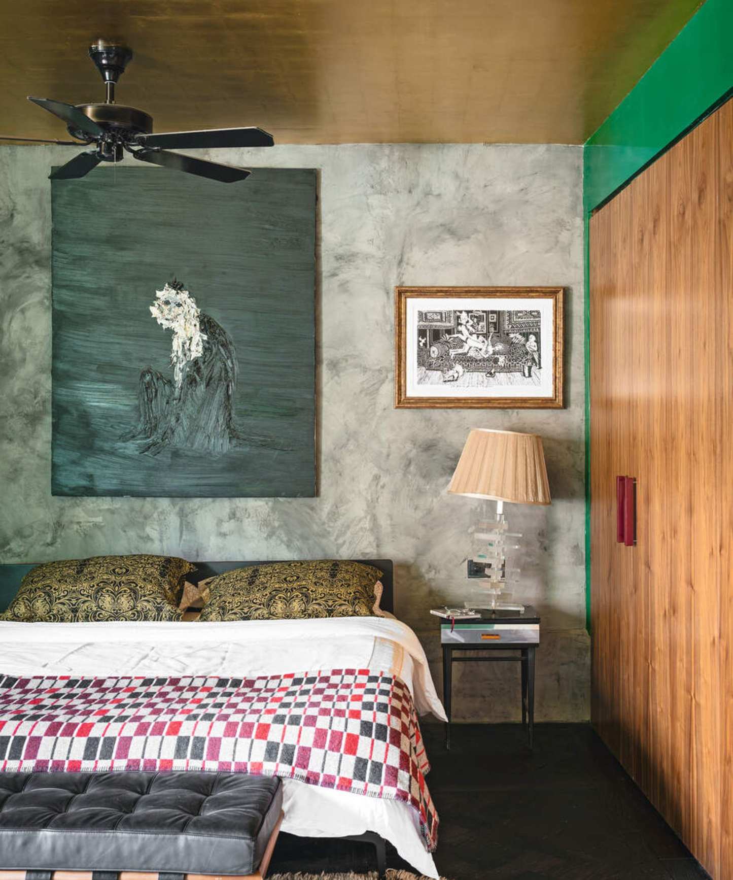 An eclectic bedroom with a gold foil ceiling, a ceiling fan and a large painted canvas above the bed