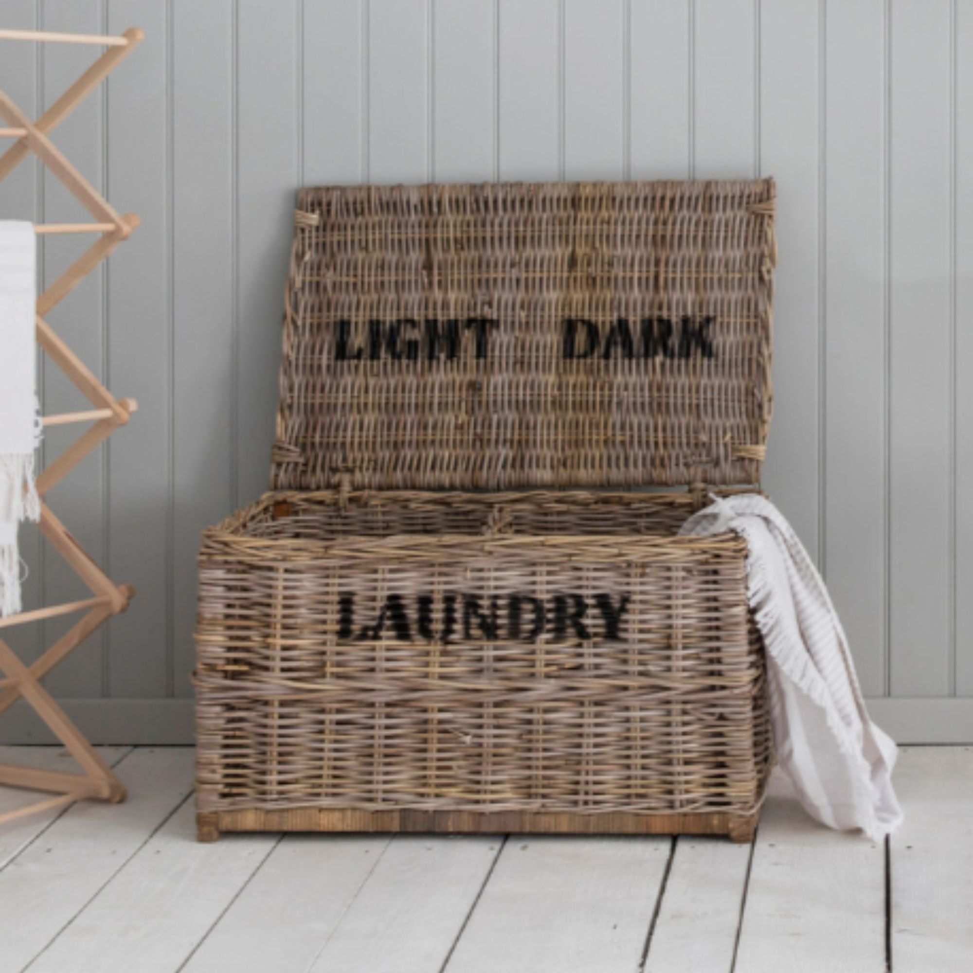 Garden Trading Dark and Lights Laundry Chest on a white wood floor, next to a wooden airer
